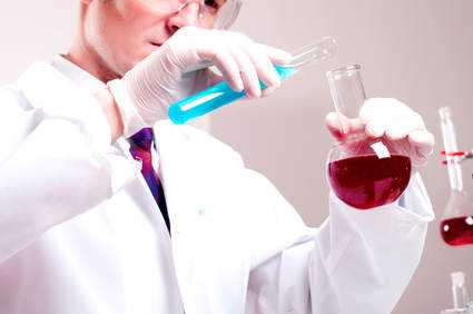 Scientist in white coat and safety glasses holding test tubes in lab